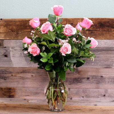dozen pink roses in a glass vase.