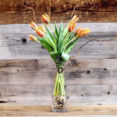 arrangement of orange tulips in a tall, slim glass vase