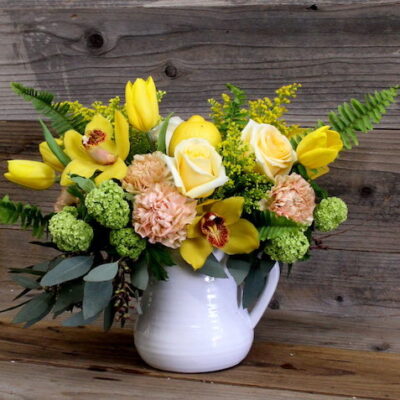 yellow and pink flowers in a white pitcher vase