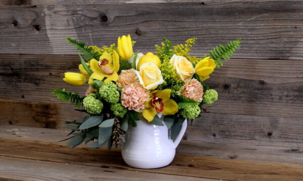 yellow and pink flowers in a white pitcher vase