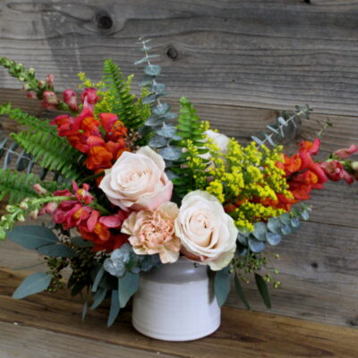 small flower arrangement with eucalyptus leaves and roses in a white pot