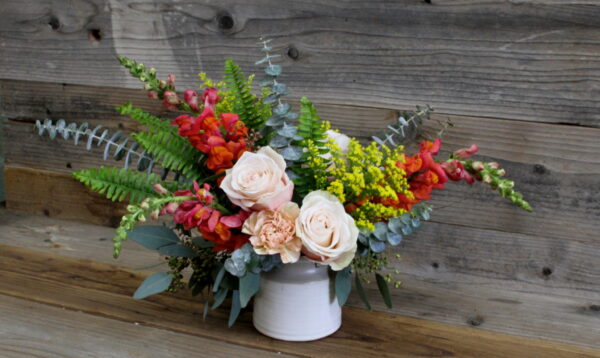 small flower arrangement with eucalyptus leaves and roses in a white pot