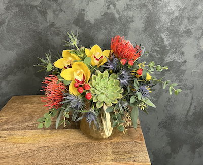 small flower arrangement of orchids and succulents in a gold vase