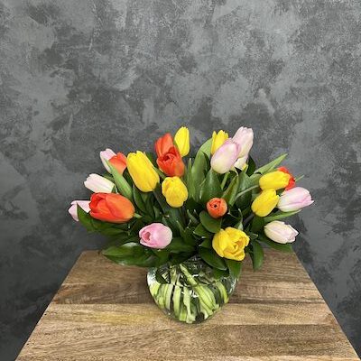glass vase filled with multi colored tulips
