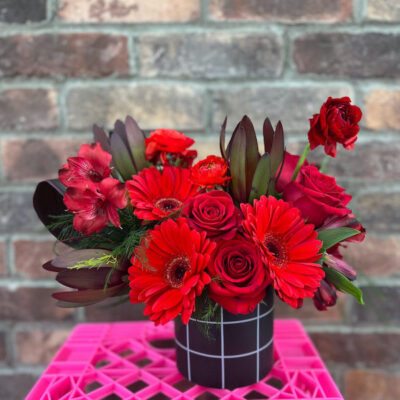 small vase on a pink crate filled with red flowers