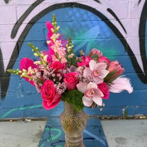 pink themed flowers and feathers in a vase behind a colorful wall