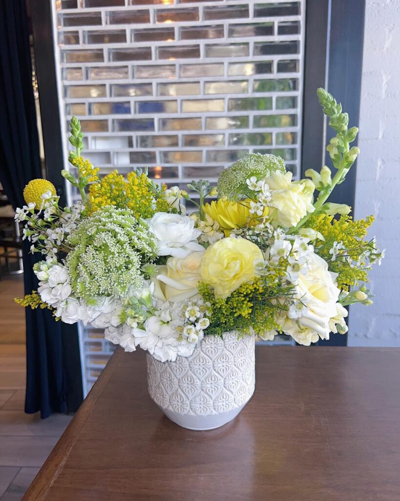 a large flower arrangement in a white vase on a table at a business