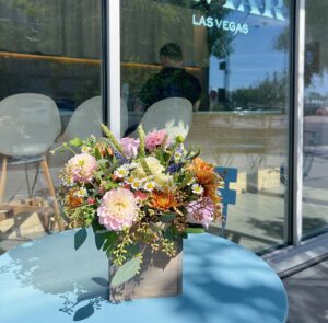 vase of flowers on a blue table outside of a store