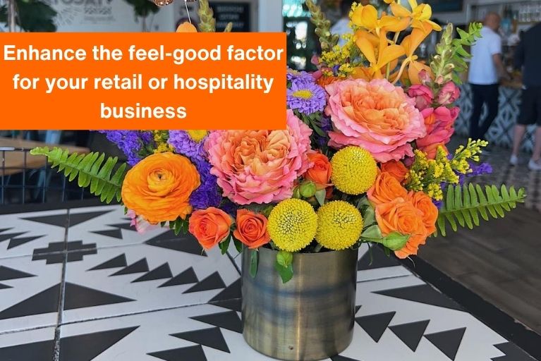 colorful flowers in a vase on a table at a restaurant with text overlayed on the image that reads 'enhance the feel-good factor for your retail or hospitality business'