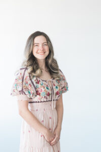 woman in a white floral dress standing in front of a white wall