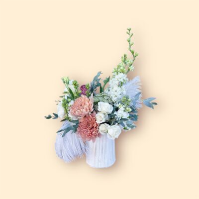 white and rust colored flowers, greenery, and ostrich feathers in a white vase for valentines day gift