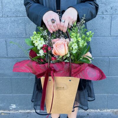 person holding a brown gift bag filled with pink roses for valentines day gift