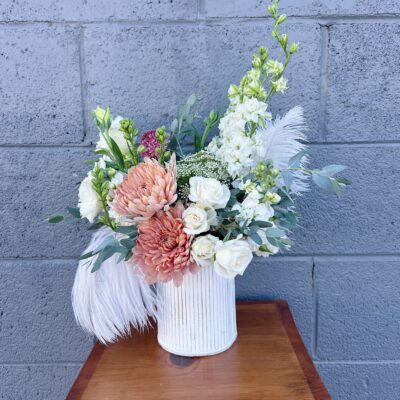 white and rust colored flowers, greenery, and ostrich feathers in a white vase for valentines day gift