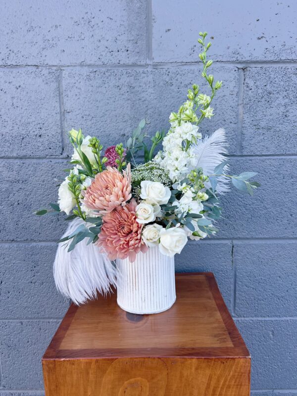 white and rust colored flowers, greenery, and ostrich feathers in a white vase for valentines day gift