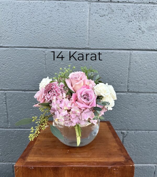 pink flowers in a clear glass vase for valentines day, the word '14 karat' above it