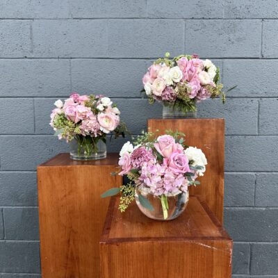 set of three valentines day flower arrangements in clear vases filled with pink flowers