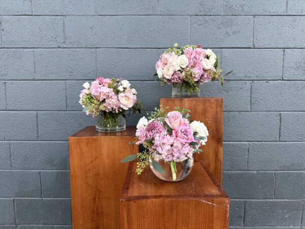 set of three valentines day flower arrangements in clear vases filled with pink flowers