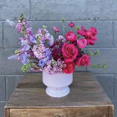 purple and red valentines day flower arrangement in a white vase