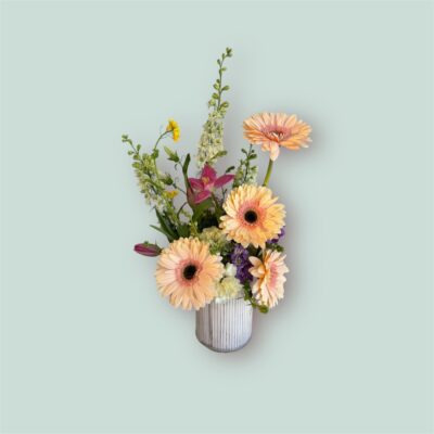 peach gerbera daisies and wildflowers in a ceramic vase